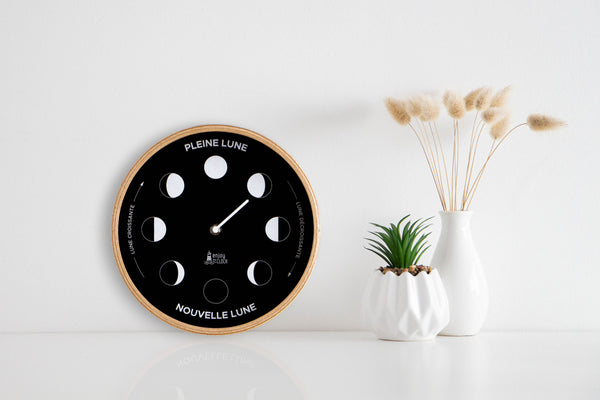 Horloge lunaire avec un contour en bois naturel et un fond noir, posée sur une étagère 